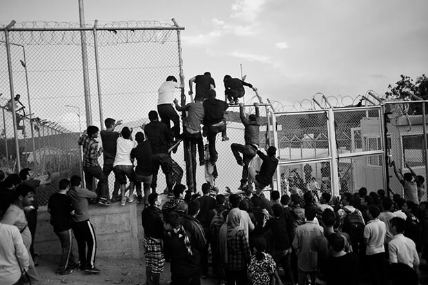 Hundreds of refugees wait for their registration in Moria, Lesbos as the police starts to use teargas because of riots between people from Irak and Afghansitan. Chaotic registration queues leave refugees in future Hot Spot under inhumane conditions for days. Here they start to climb the fences an try to enter the registration point.